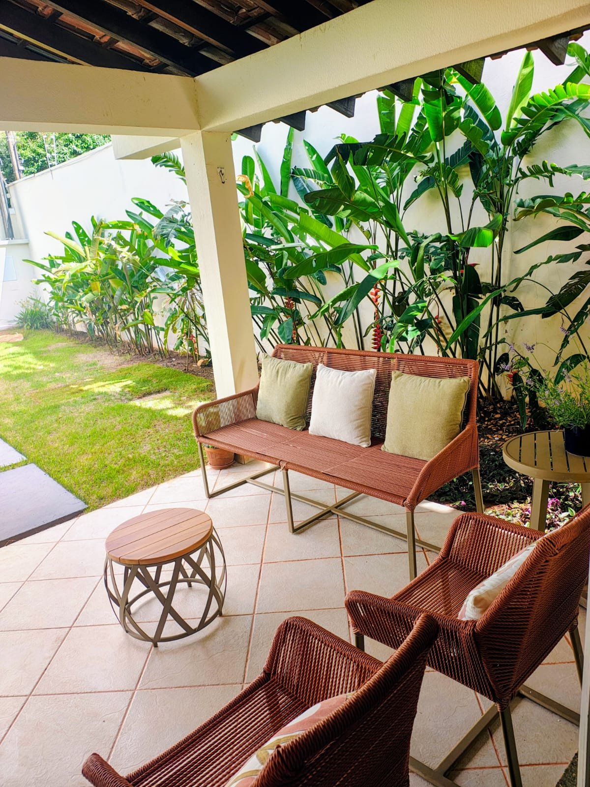 Varanda do consultório com plantas tropicais e mobiliário de fibra natural
